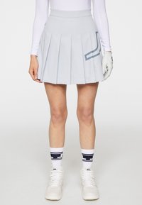 Jasnoniebieska plisowana spódnica z gładką talią oraz akcentem w geometryczny wzór. Noszona z białymi trampkami i granatowymi skarpetkami w wzory.