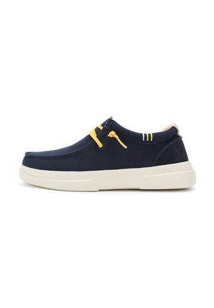 Navy canvas shoes with yellow accents, featuring a rounded toe, white sole, and minimalistic design. Notable hardware includes elastic laces.