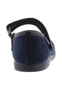 Zapato azul marino con una parte superior suave y texturizada, una correa de charol negro y una suela de goma plana. Vista trasera que muestra un diseño cosido.