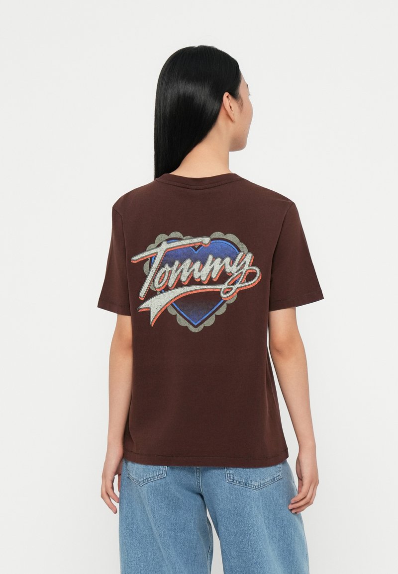 Brown cotton t-shirt featuring a large blue heart graphic with "Tommy" in white and red cursive, outlined in gray, on the back.