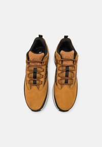 Bruna läderskor för vandring med svarta accenter, strukturerad yta, snören och vadderad krage. Bred tåkappa och robust gummisula.