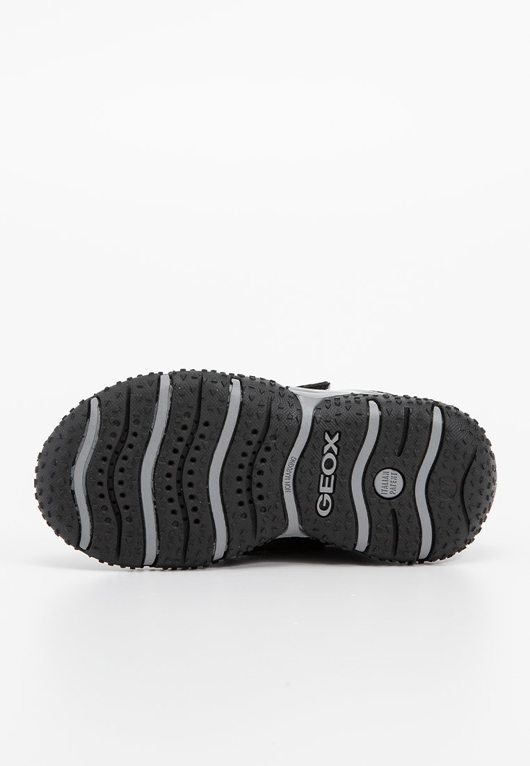 Schwarze Gummisohlen mit einem wellenförmigen Design, versehen mit grauen Streifen und kleinen runden Perforationen. Mit "GEOX" an der Seite brandmarkiert.