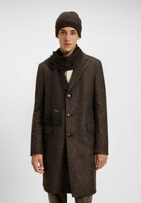 Brown patterned wool overcoat with notched collar, three buttons, and two side pockets, paired with a matching dark brown knit hat and scarf.