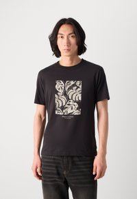 T-shirt in cotone nero con un motivo a foglia color crema e un logo in basso. Maniche corte e scollo rotondo.