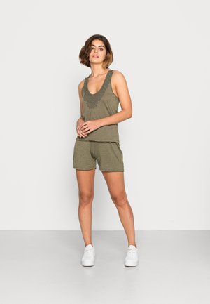 Top de algodão verde-oliva com decote bordado, combinado com calções a condizer. Modelo usa sapatilhas brancas; design limpo e simples.