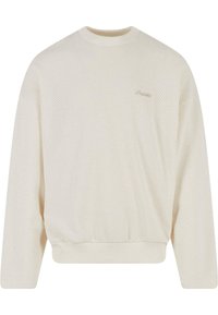 Hellbeige Sweatshirt aus strukturiertem Strick, mit Rundhalsausschnitt, überschnittenen Schultern und geripptem Saum. Dezentes Branding auf der Brust.