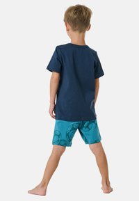 Navyblauw katoenen t-shirt, met korte mouwen, gecombineerd met turkooise shorts met een patroon van voetballen.