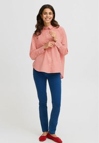 Red and white striped button-up shirt with a collar, long sleeves, and a pocket. Worn with blue jeans and red flats.