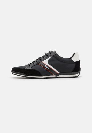 Sort lavtop sneakers med hvide og orange sidelister, sorte snørebånd, ruskindstå og hvid hælskinne, mærket "BOSS" på siden.