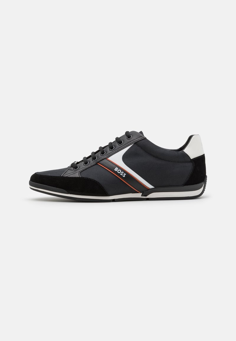 Baskets basses noires avec des bandes latérales blanches et orange, lacets noirs, bout en daim et languette de talon blanche, marquées "BOSS" sur le côté.