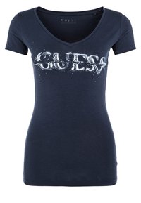 Marineblauwe v-hals t-shirt van zachte katoen, met een gedurfde witte "GUESS" logo met een vervaagd effect over de borst.