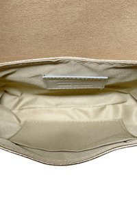 Interno della borsa foderato in tessuto beige con etichetta cucita che riporta "100% pelle di mucca, fatta in Italia."