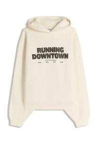 Krémová mikina s kengúrskou kapsou, spadnutými ramenami a grafickým potlačou s nápisom "RUNNING DOWNTOWN" v tučných čiernych písmenách.
