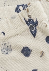 Katoenen stof met een crèmekleurige achtergrond, versierd met blauwe en beige hemelpatronen, waaronder planeten en sterren. Gevoel voor gestructureerde brei-details is zichtbaar.