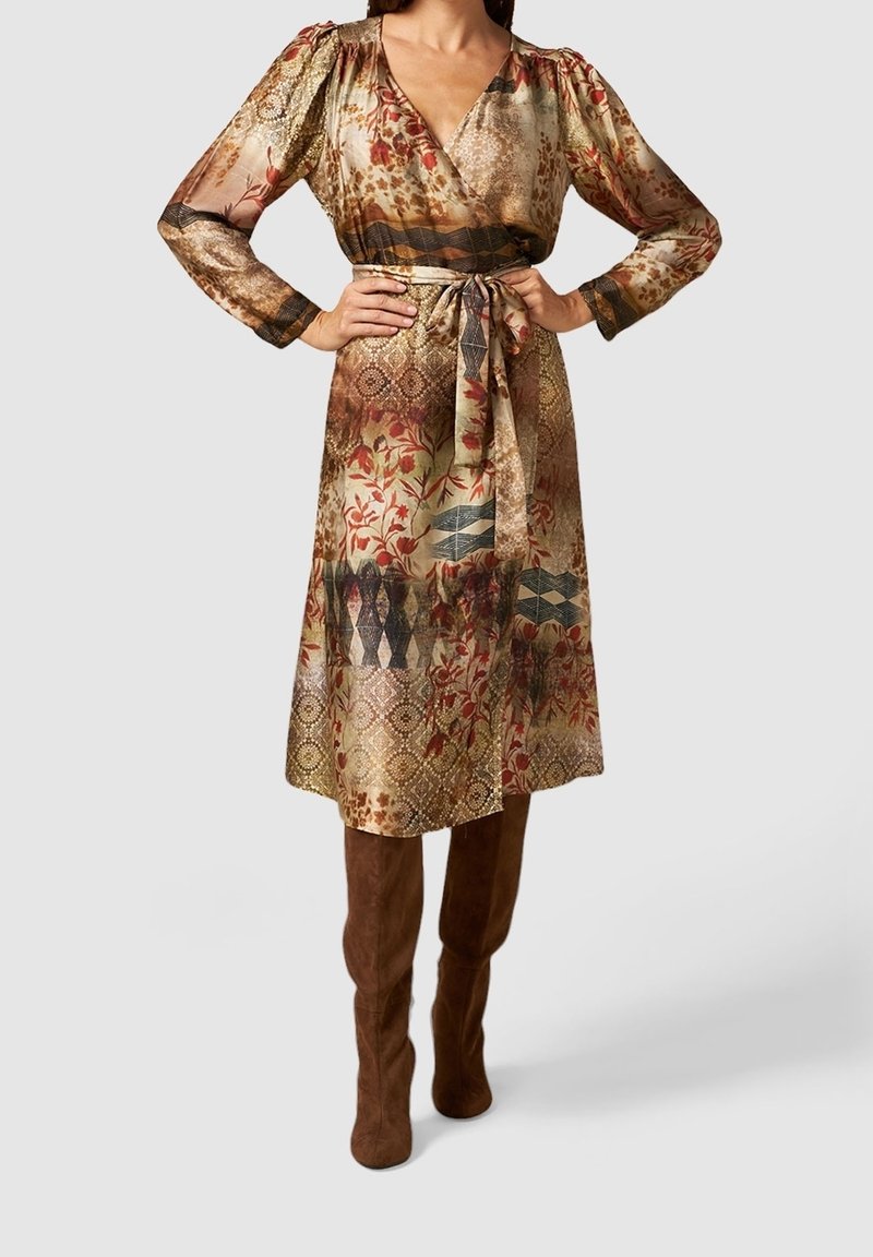 Robe longue à motif floral dans des tons dorés et terre. Conçue avec un effet portefeuille, elle possède des manches longues, une taille cintrée et une ceinture assortie.