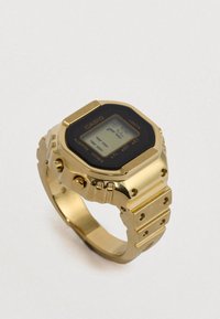 Reloj digital de oro con una esfera rectangular negra que muestra la hora, con una correa metálica de eslabones distintos y detalles texturizados.