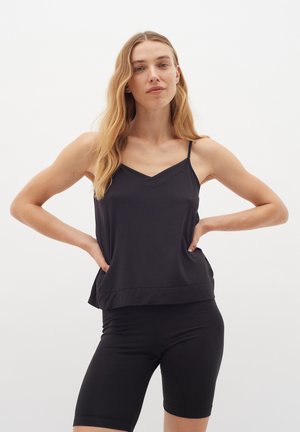 Black tank top with v-neckline, thin straps, and a relaxed fit, paired with black bike shorts featuring a fitted design. Smooth fabric texture.