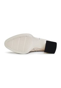 Semelle de chaussure à talon beige avec une forme lisse et arrondie, une prise texturée et un accent en caoutchouc noir au niveau du talon. Détails de couture visibles.