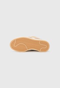 Sneaker sole with a textured, herringbone pattern. Color is light tan with subtle accents and a flattened, rounded shape.