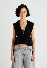 Mustmust mustriga crop-top mustriga seotava kinnitusega, lühikeste varrukatega ja tekstureeritud kangast. Sobib laia halli teksapüksega.