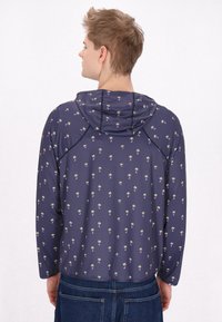 Giacca a pullover blu navy con design a fantasia di piccole palme, dotata di cappuccio e maniche lunghe, realizzata in tessuto leggero.