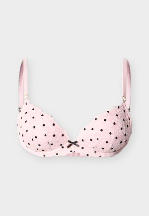 Soutien-gorge en dentelle rose clair à pois noirs, bretelles réglables et petit nœud noir au centre devant.