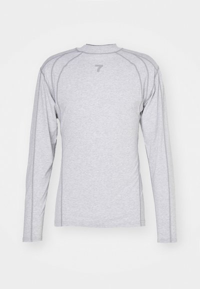 Harmaa pitkähihainen paita, joka on valmistettu kevyestä kankaasta. Paitassa on korkea kaulus, raglan-hihat ja huomaamaton logo yläselässä.