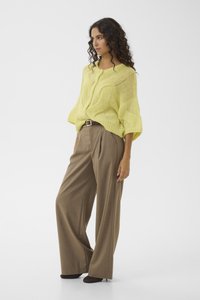 Πλεκτό πουλόβερ με κοντά μανίκια σε φωτεινό κίτρινο χρώμα, με χαλαρή εφαρμογή και υφασμένο σχέδιο, συνδυασμένο με ψηλόμεσα, καφέ παντελόνια με φαρδιά πόδια.