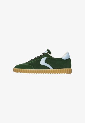 Green suede sneaker with a light blue leather accent, textured rubber sole, black laces, and padded collar. Features a curved design.