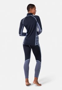 Langärmliges Oberteil und enganliegende Leggings in Dunkelblau und Grau, mit markanten geometrischen Mustern, weichem Material und kontrastierenden Akzenten.