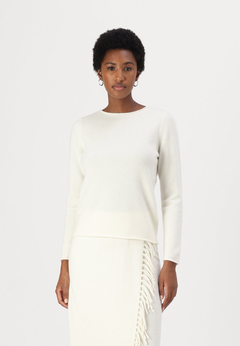 Pull en laine ivoire clair avec un col rond et des manches longues, offrant une coupe légèrement décontractée. Texture lisse sans motifs visibles.