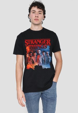 Black cotton T-shirt featuring a colorful "Stranger Things" graphic with characters, set against an orange and blue background.