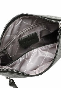 Zwarte leren tas met textuur en ritssluiting. Het interieur heeft een lichtgrijze voering met een geometrisch patroon en een klein ritsvakje.