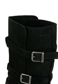 Černé semišové boty s širokým lemem, zdobené dvěma dekoračními popruhy a stříbrnými kovovými sponami. Šité detaily zvýrazňují materiál.