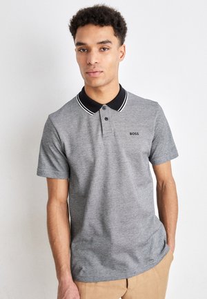 Graues Poloshirt mit schwarzem Kragen, der weiße Streifen aufweist, kurzen Ärmeln und einem kleinen Logo auf der linken Brust. Glatte Stoffoberfläche.