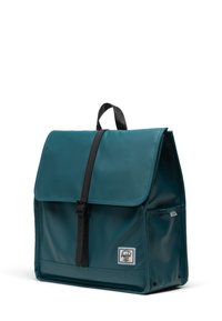 Teal waterproof backpack with a flap closure, black straps, front pocket, and a white brand label at the bottom. Smooth texture.