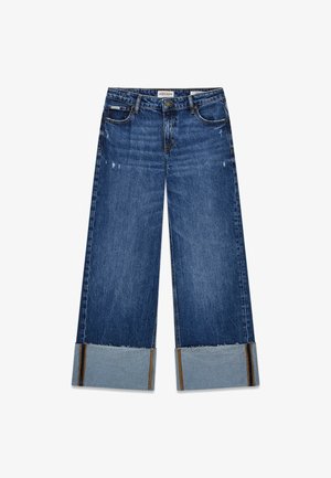 Sötét kék, széles lábú farmernadrág, elhasználtsági részletekkel. A szegők világosabb farmerrel készültek, dupla varrással.