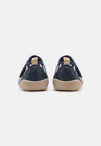 Námořnické slip-on boty s měkkým, texturovaným povrchem, béžovými gumovými podrážkami a vzorovanými elastickými bočními detaily. Zadní poutka pro snadné obouvání.