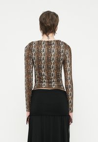 Top de mangas compridas em tecido transparente castanho com padrão de leopardo, apresentando detalhes franzidos na cintura e um decote redondo.