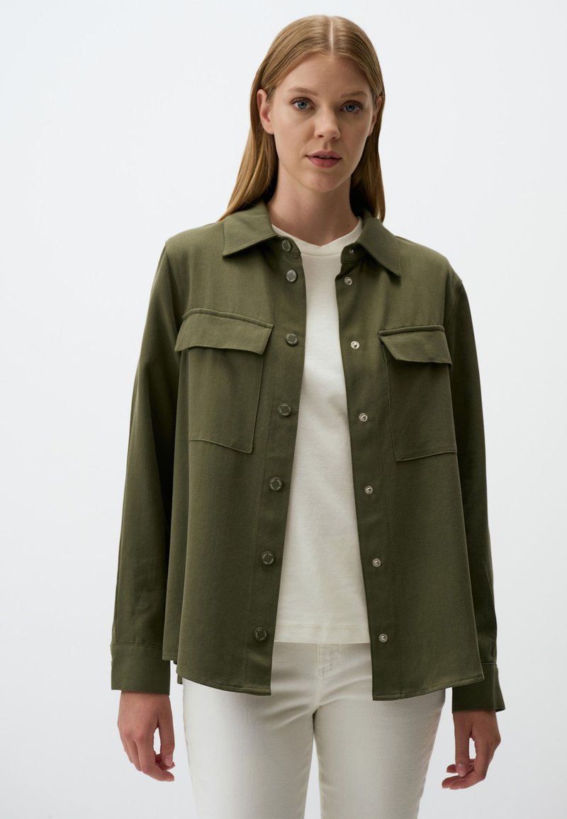 Olief groenen, langhandige shirt met knoopsluiting, twee borstzakken en een kraag. De stof lijkt glad met een matte afwerking.