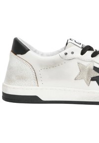 Sneaker bianco in pelle con un accento a stella argentata texturizzata, occhielli neri e un tallone nero. Suola in gomma bianca con bordo nero.