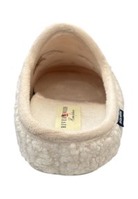 Chausson d'intérieur beige avec un extérieur texturé et duveteux, doublure douce et étiquette logo à l'intérieur ; forme arrondie et semelle rembourrée.