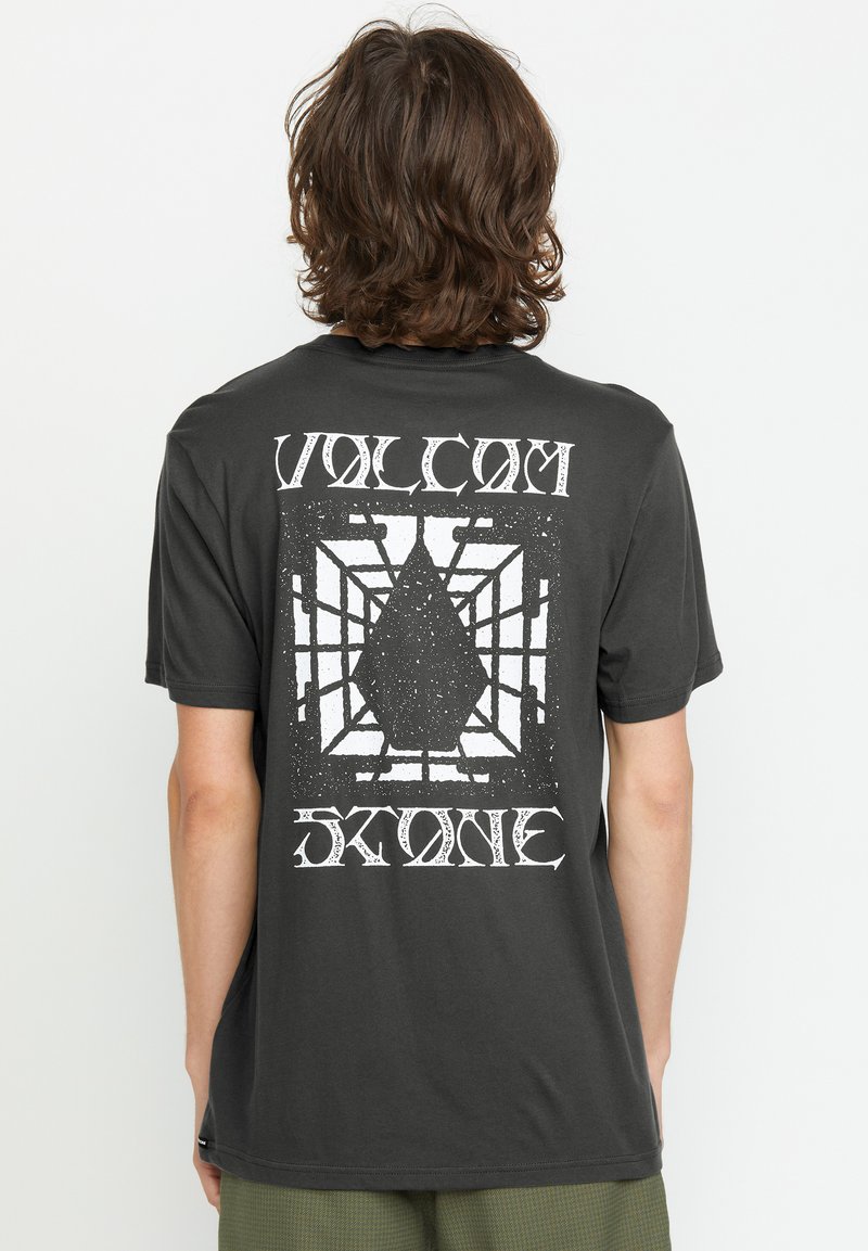 Sort bomulds T-shirt med et stort hvidt grafisk design på ryggen, der viser en diamantform i et netlignende mønster.