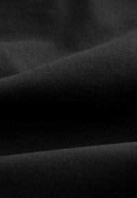 Czarna tekstura tkaniny o gładkiej, matowej powierzchni z drobnym splotem. Brak wzorów, delikatne fałdy tworzą miękkie cienie.