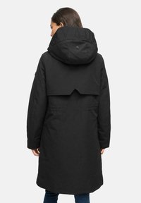 Zwarte geïsoleerde parka met een kortere achterkant, capuchon en reliëflettering op de kraag. Heeft een gladde matte textuur.
