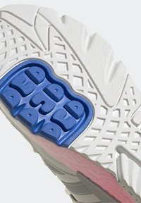 Podeszwa buta sportowego z fakturowanym białym gumowym dołem, jasnoszarym wierzchem, niebieskim poduszką amortyzującą i różowymi akcentami, zaprojektowana z myślą o przyczepności.