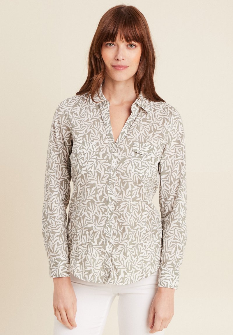 Lichtgewicht blouse in lichtbeige met wit bladerenpatroon, voorzien van een kraag en twee borstzakken, lange mouwen en een losse pasvorm.