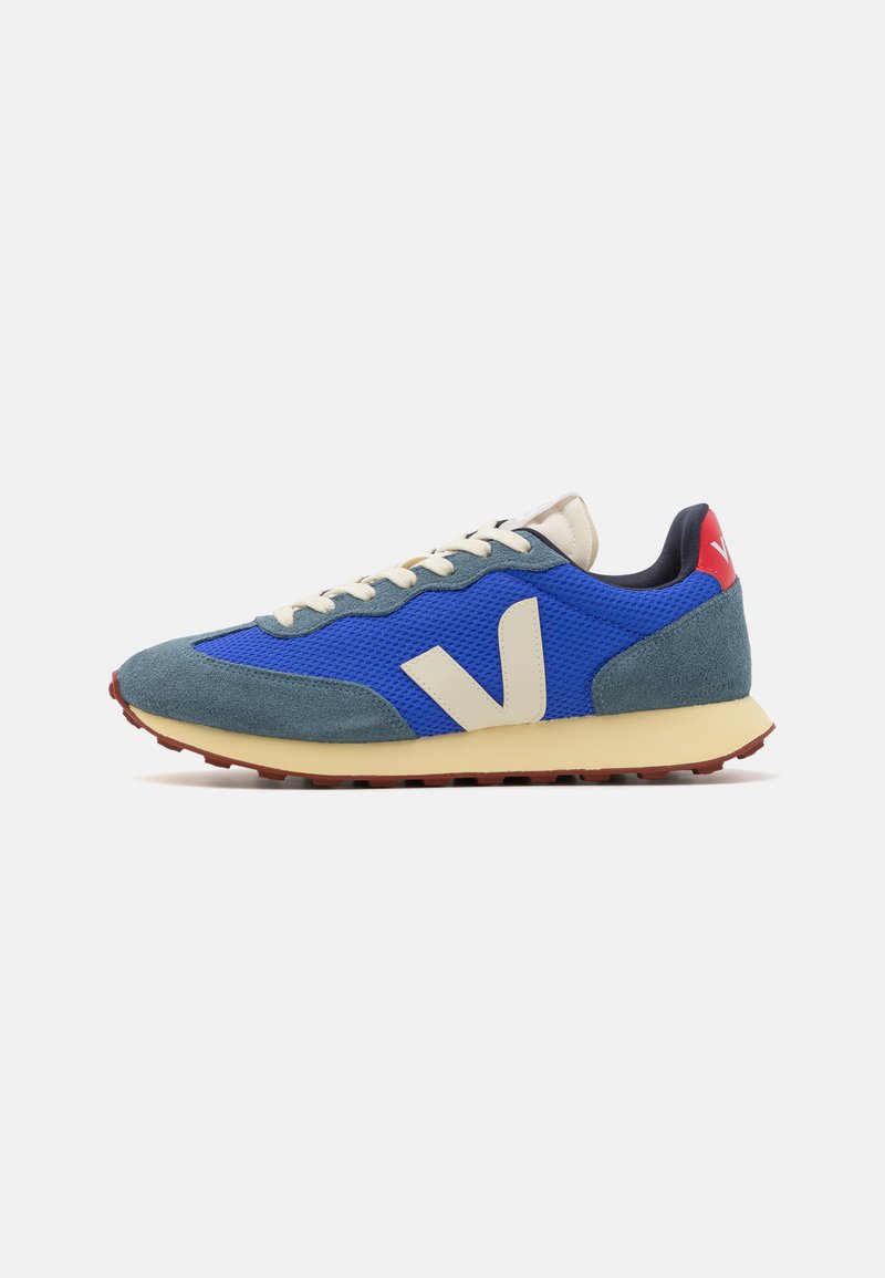 Blue and grey sneakers with a textured mesh and suede upper, cream laces, and a red heel accent. Features a white "V" logo on the side.