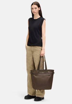 Braune Leder-Tote mit zwei Oberhandgriffen, rechteckiger Form, glatter Textur und minimalistischem Design, getragen von einem Modell in neutraler Kleidung.