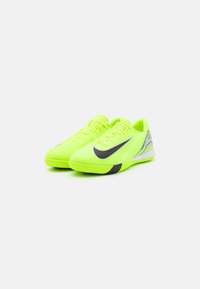 Neona dzeltenas sporta kurpes ar teksturētu virsotni, melnu Swoosh logo un pelēkiem akcentiem uz papēža un sāniem. Šņorējams dizains. Gumijas zole.